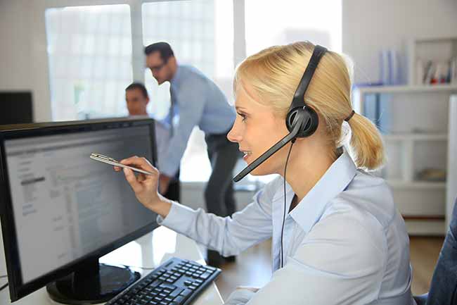 Women wearing headset pointing at computer screen